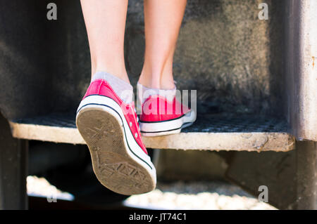 Girl entering a vintage train wearing red sneakers close up Stock Photo