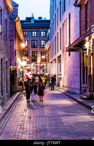 Montreal, Canada - May 27, 2017: Old town area with people walking up cobblestone street in evening outside restaurants in Quebec region city Stock Photo