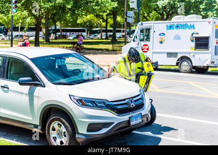 Washington DC, USA - July 3, 2017: Police traffic officer writing ticket for car illegally parked while riding segway on national mall Stock Photo