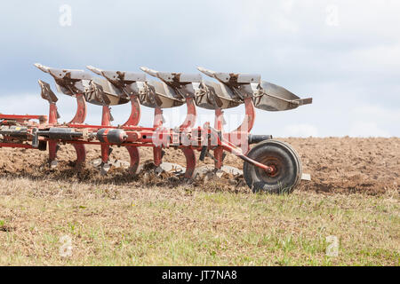 Close up detail of an agricultural plough in action ploughing a fallow overwintered  field turning the earth in preparation for the planting of the sp Stock Photo