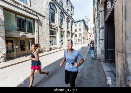 Montreal, Canada - May 28, 2017: Old town area building with women smiling and running by street in Quebec region city in morning Stock Photo