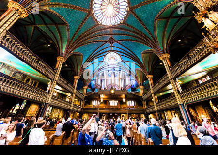 Montreal, Canada - May 28, 2017: Inside Notre Dame Basilica during mass with many people taking pictures of detailed architecture and organ Stock Photo