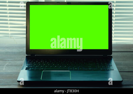 low key shot of opened black notebook on a dark desk with green screen for your data information. close view in office with closed blinds Stock Photo