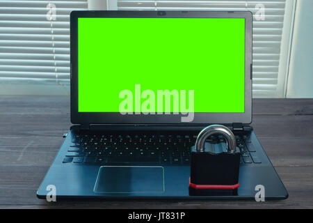 concept image of information security. big metal lock on a laptop with green screen. protect your data from hack, scam, fraud, phishing Stock Photo