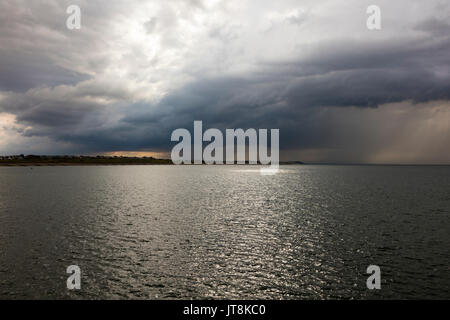 Herne Bay, Kent, UK, 8th August 2017. UK Weather News. A drizzily summers day at Hampton Herne Bay, ends with dark clouds and thunderstorms appearing over the Thames Estuary with a view towards Tankerton and the Swale Estuary. Some sun breaks through the dark clouds. Credit: Richard Donovan/Alamy Live News Stock Photo