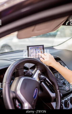 Young woman in a car using a GPS to get driving directions to her destination with model release Stock Photo