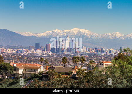 Snowed peaks mountains and downtown Los Angeles cityscape during the winter months in southern California, USA Stock Photo