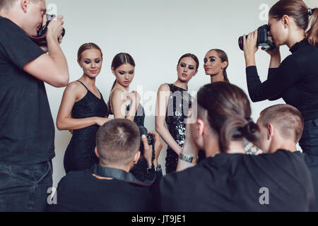 Photographers paparazzi take photos of women in cocktail dresses. Stock Photo