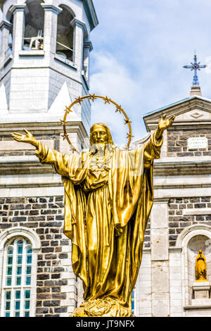 Champlain, Canada - May 29, 2017: Notre Dame de la Visitation stone church in small town on Chemin du Roy with gold Jesus Christ statue Stock Photo