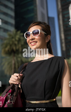 Asian business woman standing outside with office buildings in the background. Portrait of a Chinese business woman looking at the camera. Stock Photo