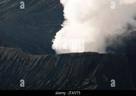 Tourists watching white smoke coming out of the active volcano crater mount Bromo from nearby at the Tengger Semeru National Park in East Java, Indone Stock Photo