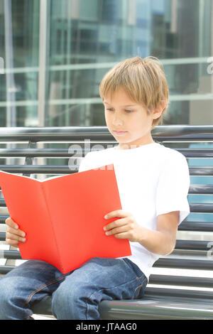 Schoolboy reading books. Child doing homework outdoors. Back to school concept. Stock Photo