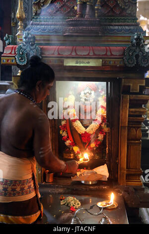 Priest with an arthi (lighted camphor) performing morning puja ceremony, Sri Thendayuthapani Hindu Temple, Singapore Stock Photo