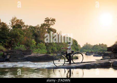 School boy on a bicycle crossing a river on his way to school, Chi Phat, Koh Kong, Cambodia, Indochina, Southeast Asia, Asia Stock Photo