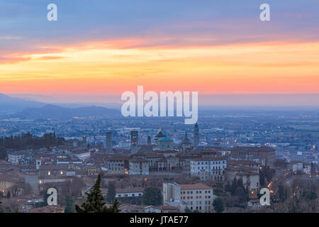 View of the medieval old town called Citta Alta on hilltop framed by the fiery orange sky at dawn, Bergamo, Lombardy, Italy Stock Photo