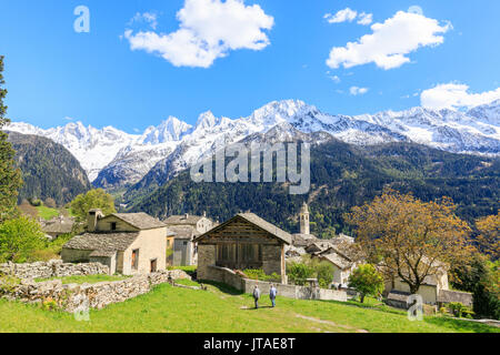 View of Soglio between meadows and snowy peaks in spring, Maloja, Bregaglia Valley, Engadine, canton of Graubunden, Switzerland Stock Photo