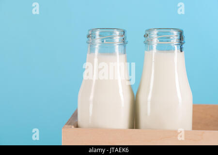 Close-up view of fresh organic milk in glass bottles in box isolated on blue Stock Photo