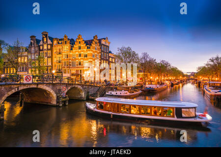 Canal scene with tour boat at dusk, Amsterdam, Netherlands, Europe Stock Photo