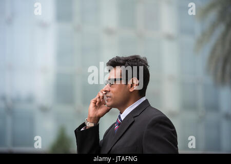 Indian businessman talking on his Smart phone outdoors in Asian city. Stock Photo