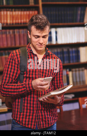 Male student using mobilephone in library Stock Photo