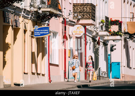 Grodno, Belarus - June 11, 2017: Two Young Women Walking Near Facades Of Old Traditional Houses In Karl Marx Street At Sunny Summer Day In Hrodna, Bel Stock Photo