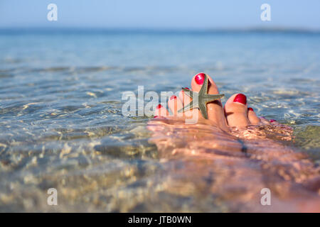 Female feet with starfish on a water Stock Photo