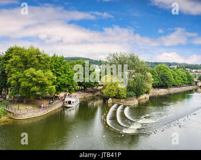 8 July 2017: Bath, Somerset, England, UK - Pulteney Weir, one of the attractions of the city, and a pleasure boat moored nearby. Stock Photo