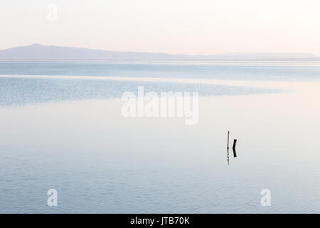 Mininalist view of a lake, with some wooden poles in the foreground and soft, blue tones Stock Photo