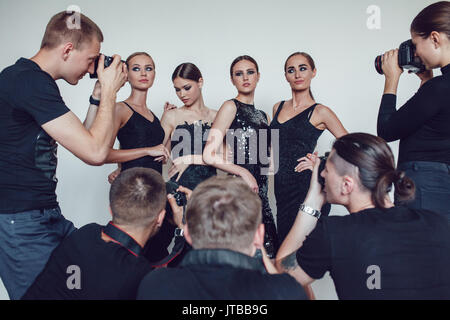 Photographers paparazzi take photos of women in cocktail dresses. Stock Photo