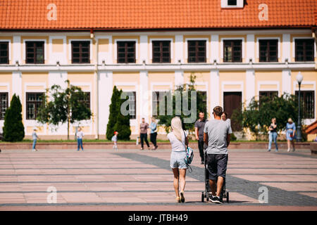 Grodno, Belarus - June 11, 2017: Young Family Couple With A Stroller Walking Near Old House Of Vice - Administrator In Sunny Summer Day In Hrodna, Bel Stock Photo