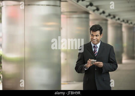 Indian business Man using his Smart phone outdoors in Asian city. Stock Photo