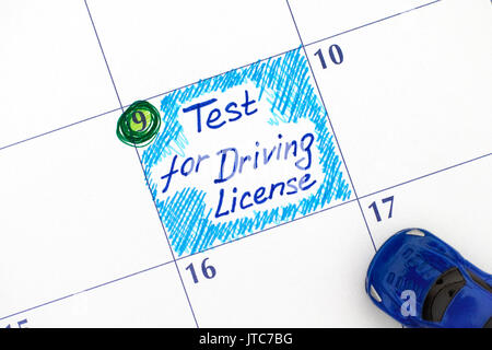 Reminder Test for Driving License in calendar with blue car toy. Close-up. Stock Photo