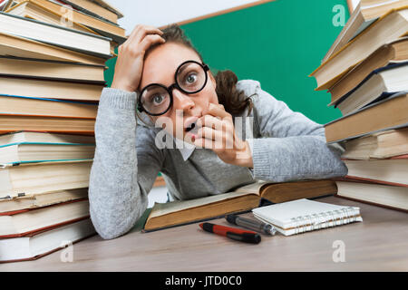 Student in shock. Photo of young girl with open mouth and big eyes, around books. Education concept Stock Photo