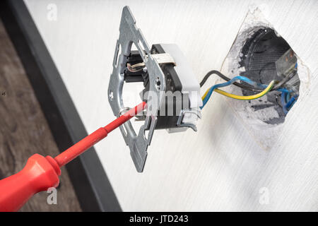 Electrician a wall socket with electronic multimeter Stock Photo