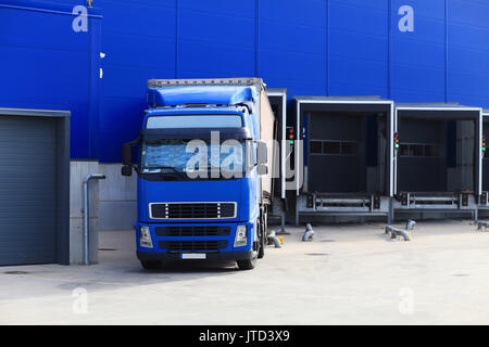 Blue truck at loading docks. Truck unloading cargo. Cargo transportation background. Stock Photo