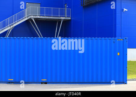 Blue cargo container on blue building background. Cargo container at storage. Stock Photo
