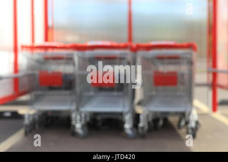 Blurred shopping background. Unfocused shopping trolleys with red handles on backdrop. Stock Photo