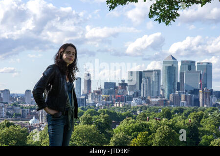 Woman stands in South London with The City of London and views of Canary Wharf in the background on a sunny day with blue skies and clouds Stock Photo
