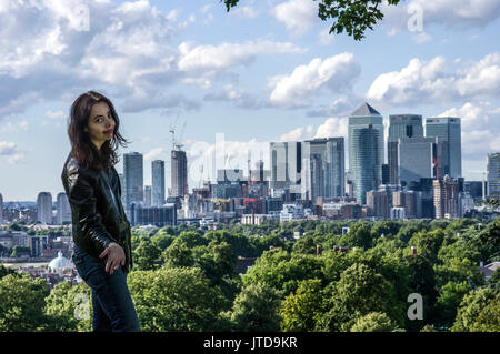 Woman stands in South London with The City of London and views of Canary Wharf in the background on a sunny day with blue skies and clouds Stock Photo