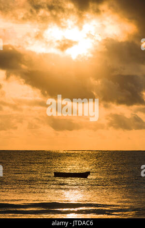 Dhow boat silhouetted in early morning sunlight breaking through clouds over Indian ocean, Diani, Kenya Dhow boat silhouetted in early morning sunlight breaking through clouds over Indian ocean, Diani, Kenya