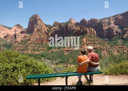 Caucasian Senior Couple (age 60-70) sitting on bench with arms around each other at Kolob Canyons at Zion National Park Springdale Utah USA. Stock Photo