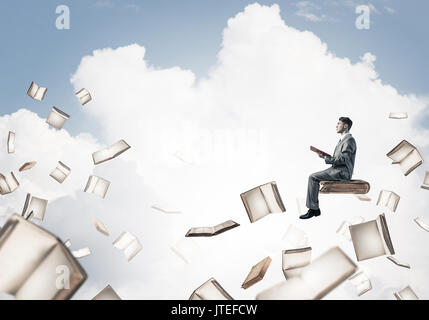 Man reading book and many of them flying in air Stock Photo