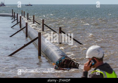 A new flood water outfall pipe has been transported by ship from Norway to the coast of Ireland and is now installed at Anchorsholme Beach, Blackpool, Lancashire. August 2017. This new extended submerged outfall pipe will discharge the excess screened stormwater out to sea and is part of improvements to the Fylde coast water management system. Filled with air to keep it afloat, the 20,000-tonne pipe left Ireland on Saturday afternoon and was pulled across the Irish Sea with an escort of 4 ships. Stock Photo