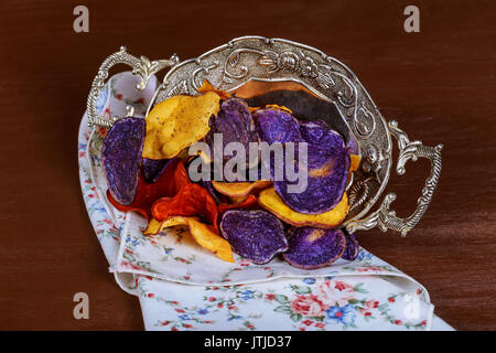 Crunchy appetizer of potato chips made from Crimson red, Purple Majesty and Chipeta, Atlantic potatoes. Potato chips in red, white and blue in a glass Stock Photo
