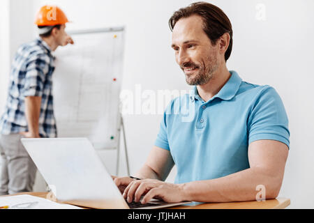 Bristled man typing an email on his laptop Stock Photo