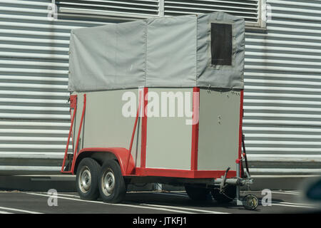 Old horse transport trailer in front of a metal wall. Stock Photo