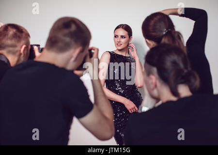 Photographers paparazzi take photos of woman in cocktail dresses. Stock Photo