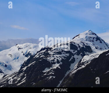 Blue sky and snow capped mountain peaks in rugged Alaska Stock Photo