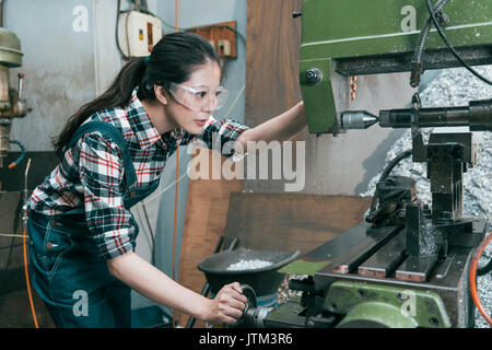 beautiful young lathe company woman worker wearing goggles adjusting milling machining doing parts components process working. Stock Photo