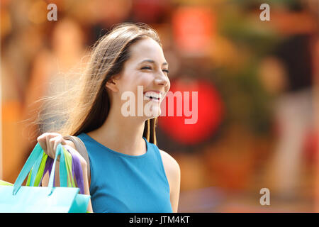 Portrait of a happy shopper with shopping bags walking on the street Stock Photo